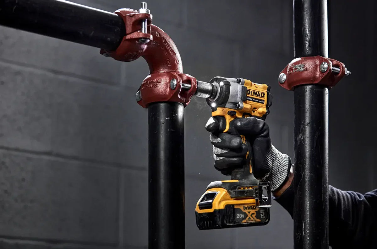 DEWALT DCF922 in-use lifestyle shot with LED light, working on pipes, yellow/black