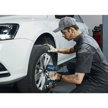 Bosch GDS 18V-400 impact wrench lifestyle shot with mechanic on car tire
